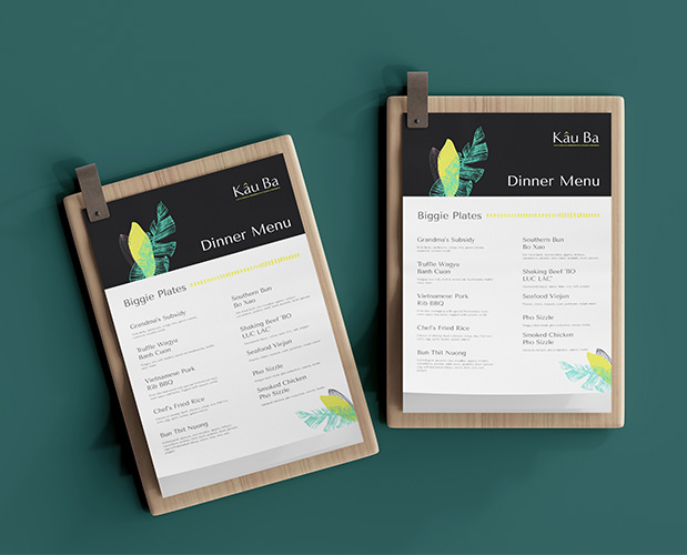 Kau Ba's new branding shown on two dinner menus laying on a green tabletop